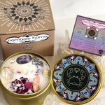 The Cancer Crystal Candle opened with the lid to the right of it. The packaging of the Cancer Crystal Candle is behind the candle next to a card.