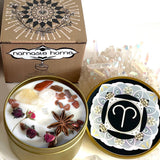 The Aries Crystal Candle opened with the lid to the right of it. The packaging of the Aries Crystal Candle is behind the candle.