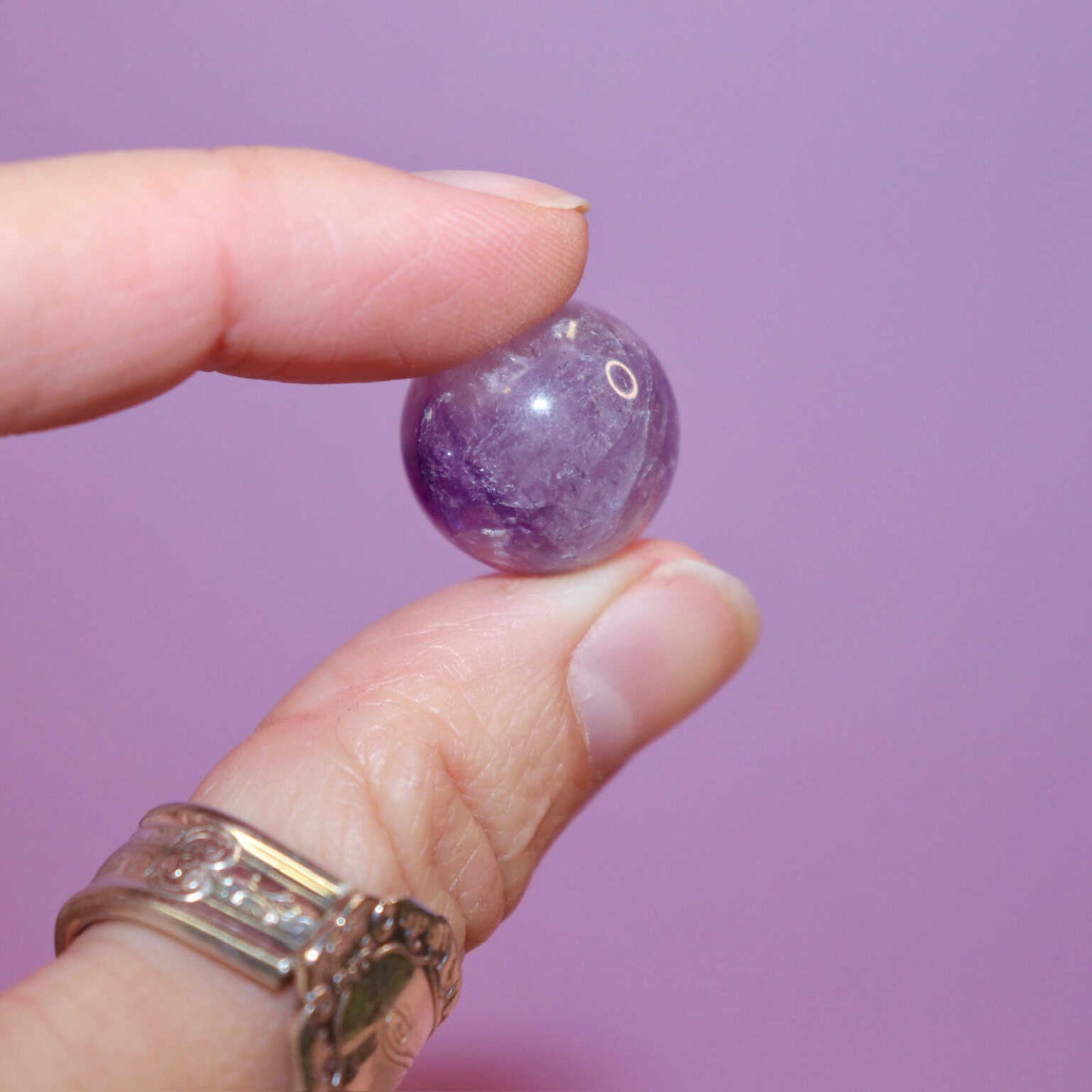 hand holding an amethyst crystal marble