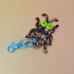 Flat lay of bug keychain with neon eyes and blue clip
