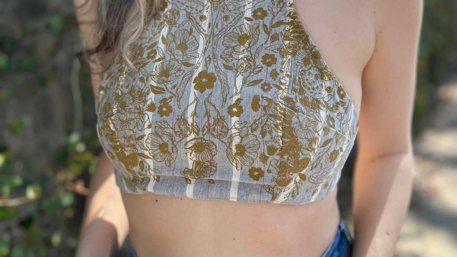 Woman wearing a floral lace crop top with a blurred natural background