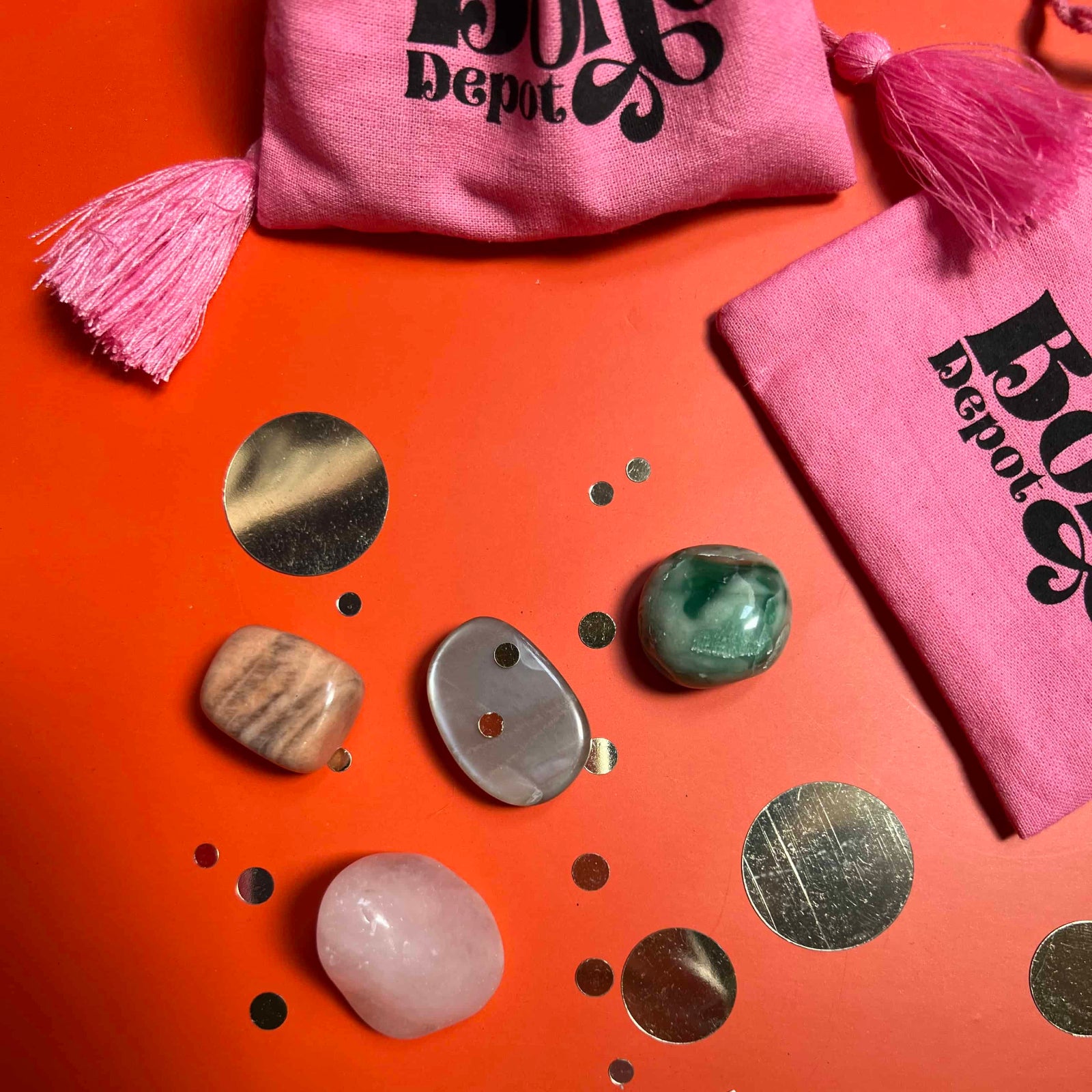 Decorative stones on an orange surface with pink bags and a smiley face sticker.