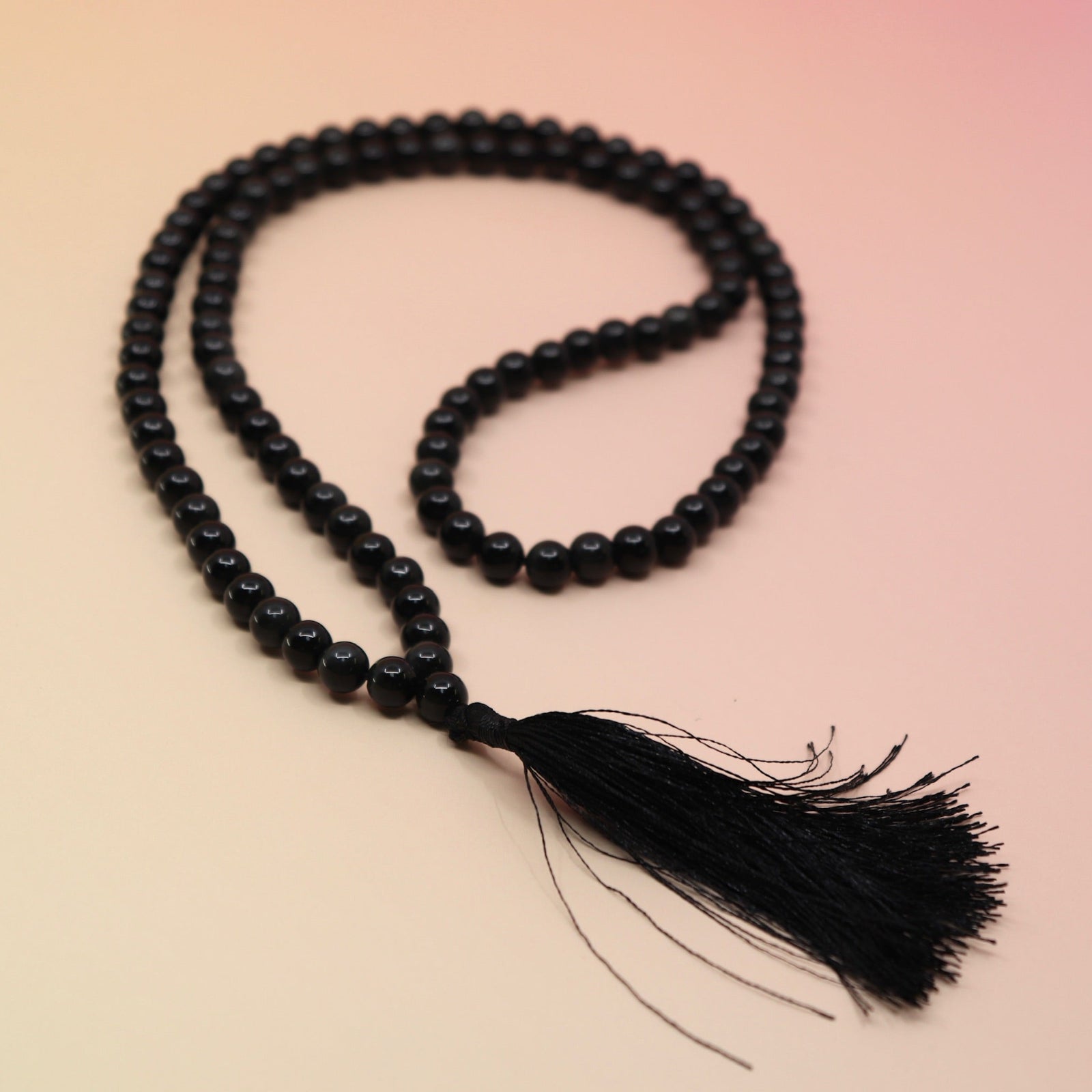 Black Obsidian 108 Mala Necklace on pink and orange background