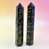 Two black crystal towers with gold moon and star patterns on a gradient background