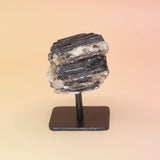 Black Tourmaline Raw Crystal Mineral on a stand against a beige background