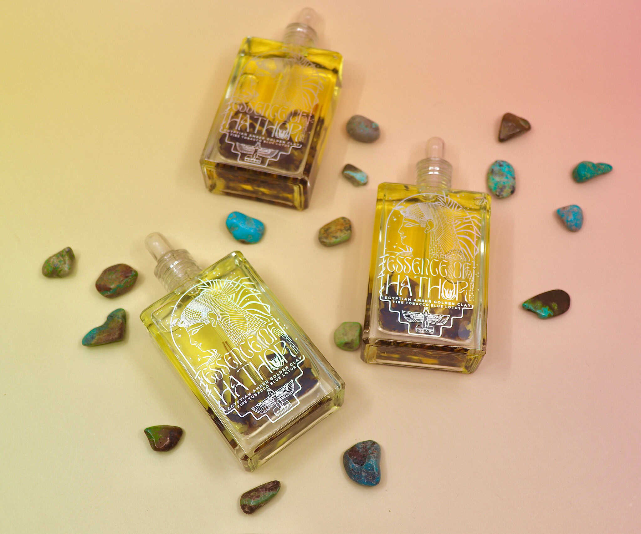 Blue Lotus Oil laid flat on a pastel pink background with turquoise stones around