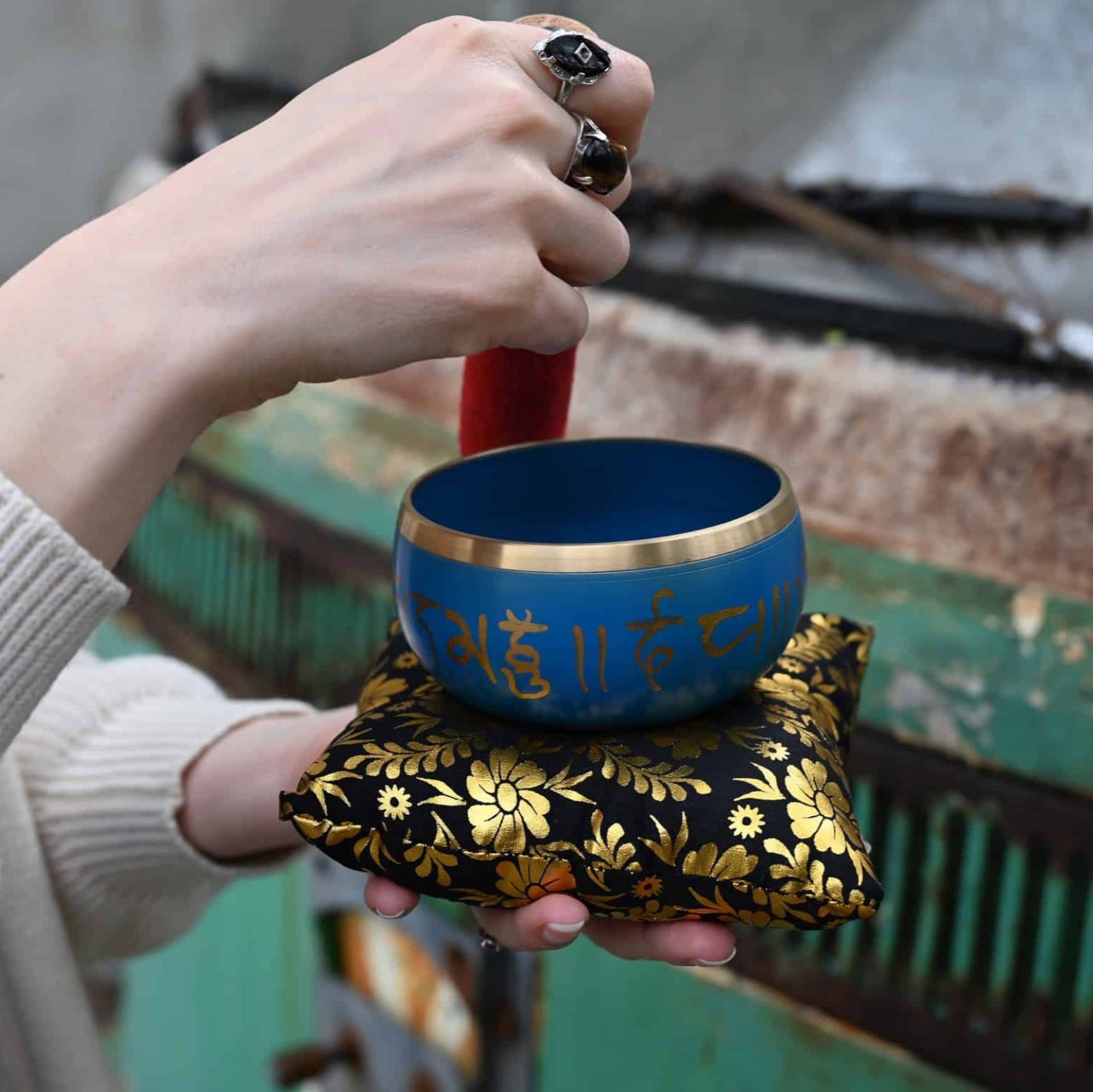 Person holding a blue singing bowl with gold accents and floral design