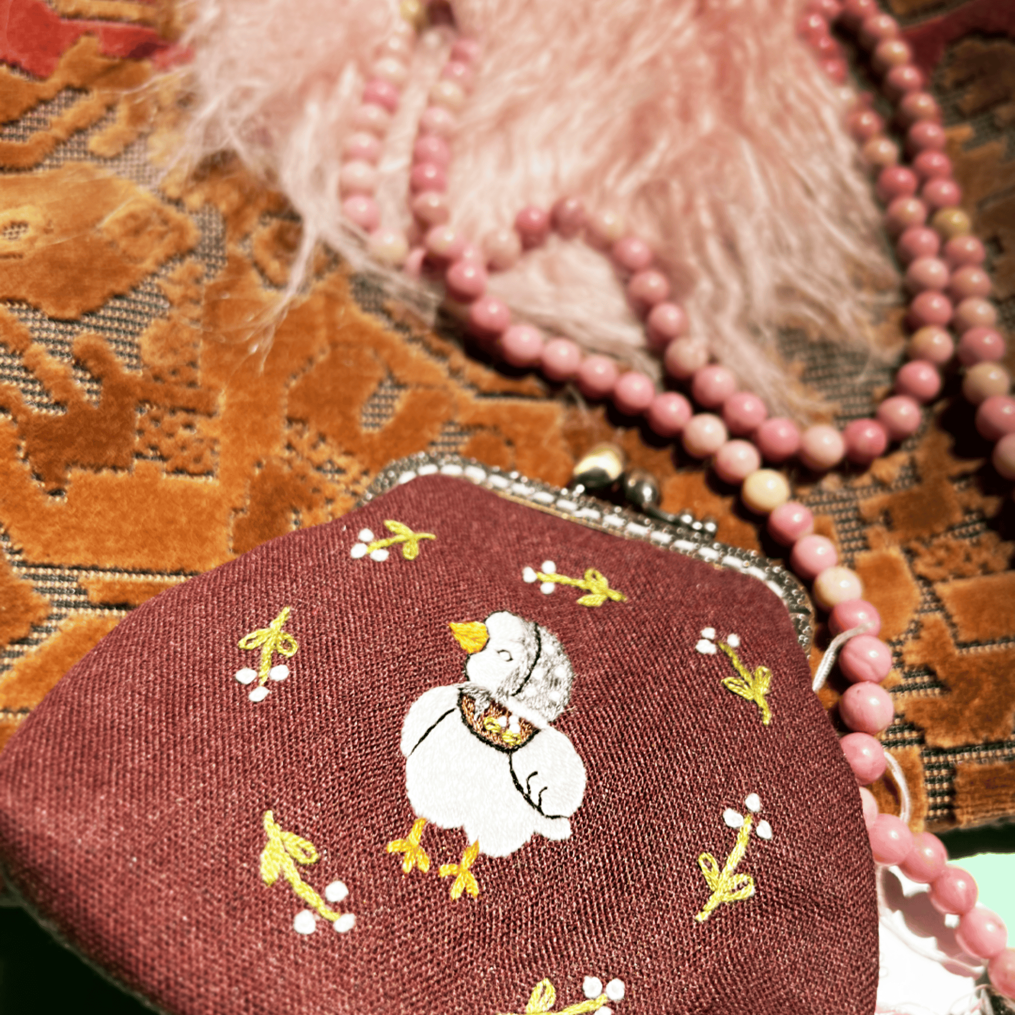 Small embroidered purse with a duck design on a textured surface