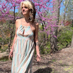 teal striped dress on model walking in front of pink trees in woods
