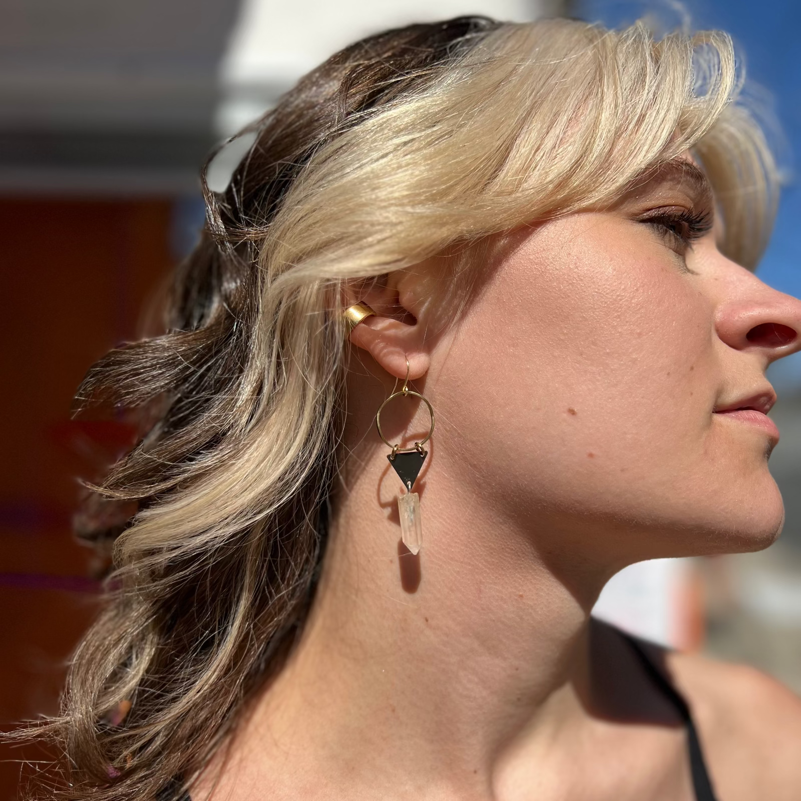 A woman wearing the Brass Quartz Crystal Triangle 2 inch. Earrings.