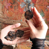 Hands holding small round objects against a colorful, textured wall.