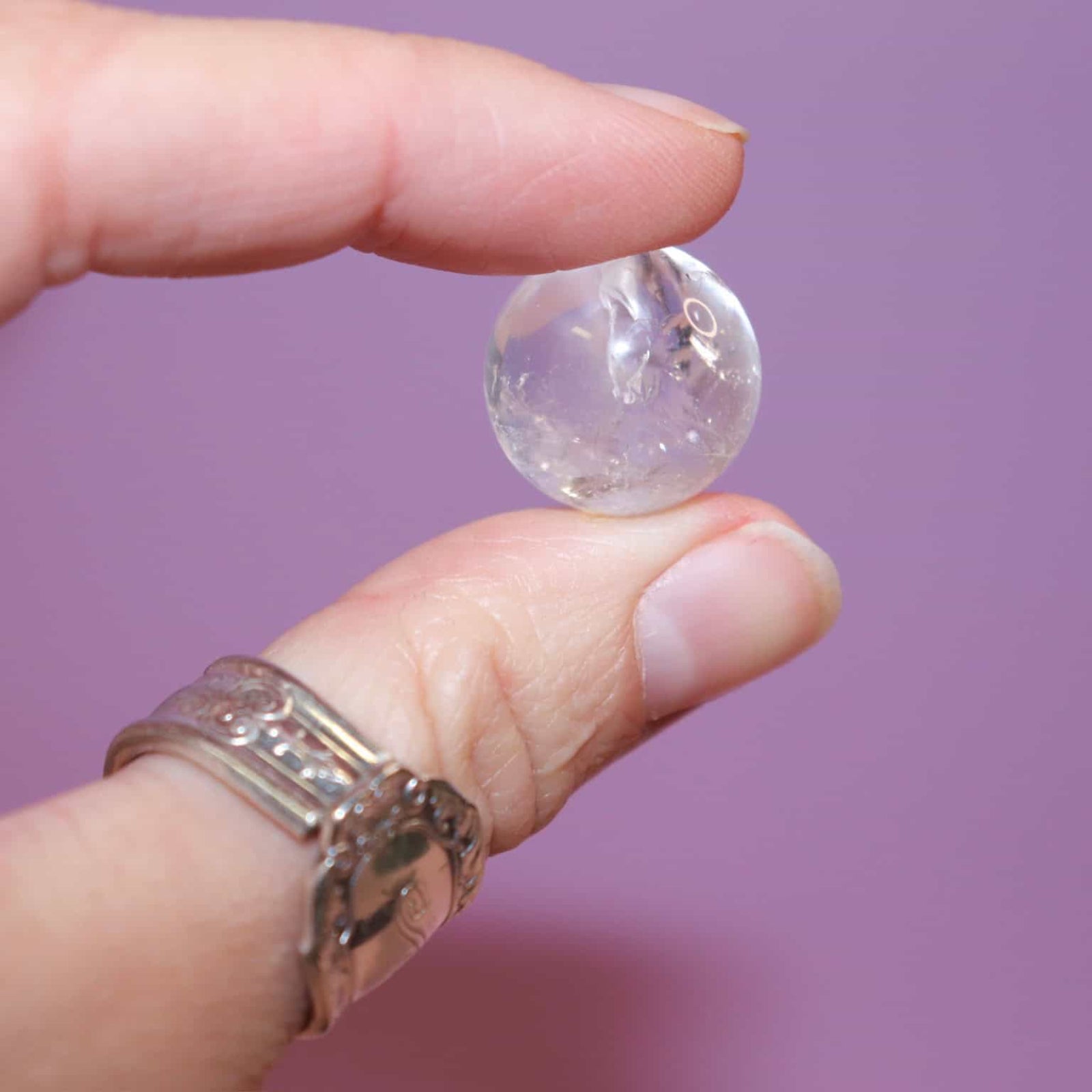 Hand holding a clear quartz marble