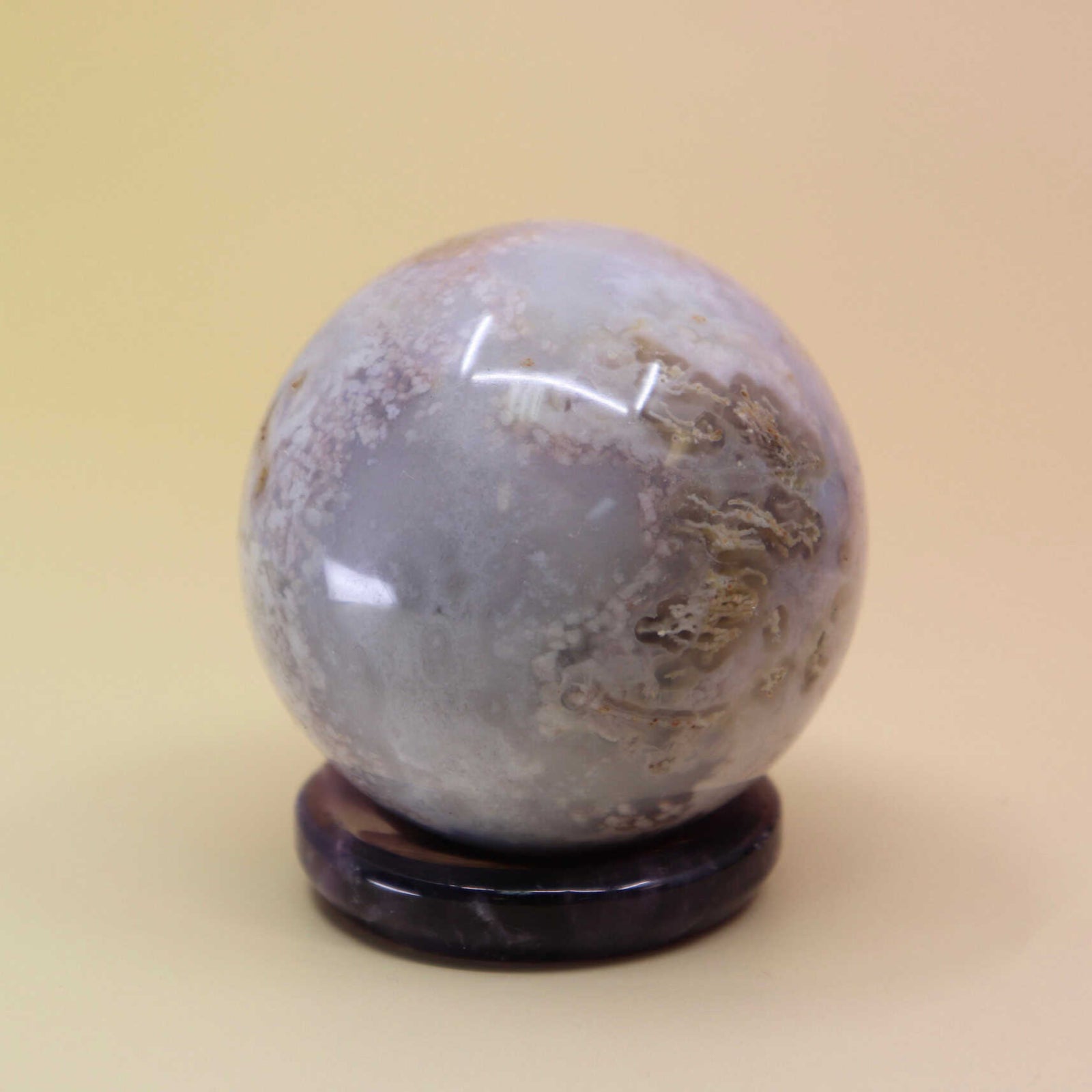 Decorative stone sphere on a stand against a beige background