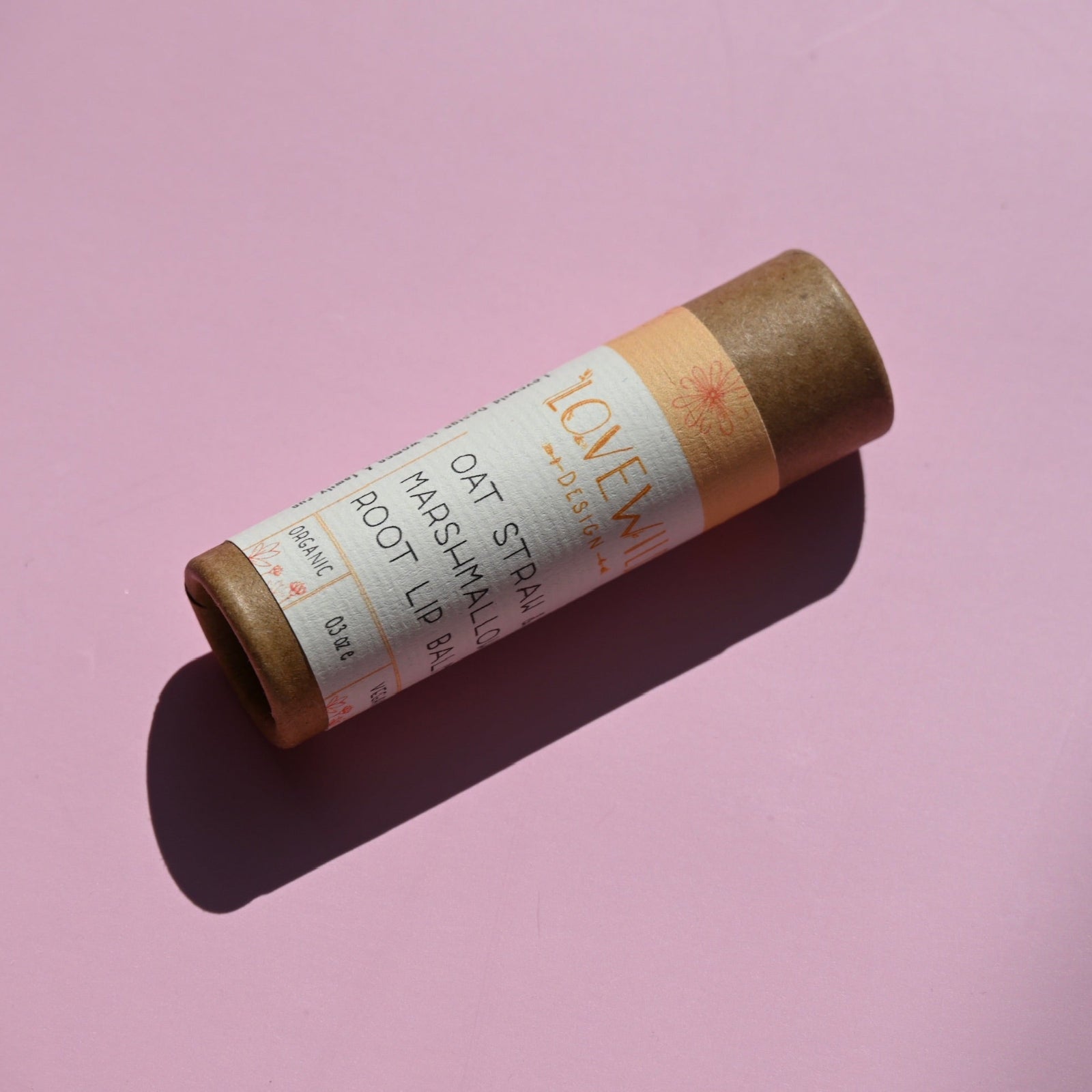 The Oat Straw and Marshmallow Root Lip Balm on a pink background.