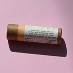 The side of the Oat Straw and Marshmallow Root Lip Balm on a pink background.
