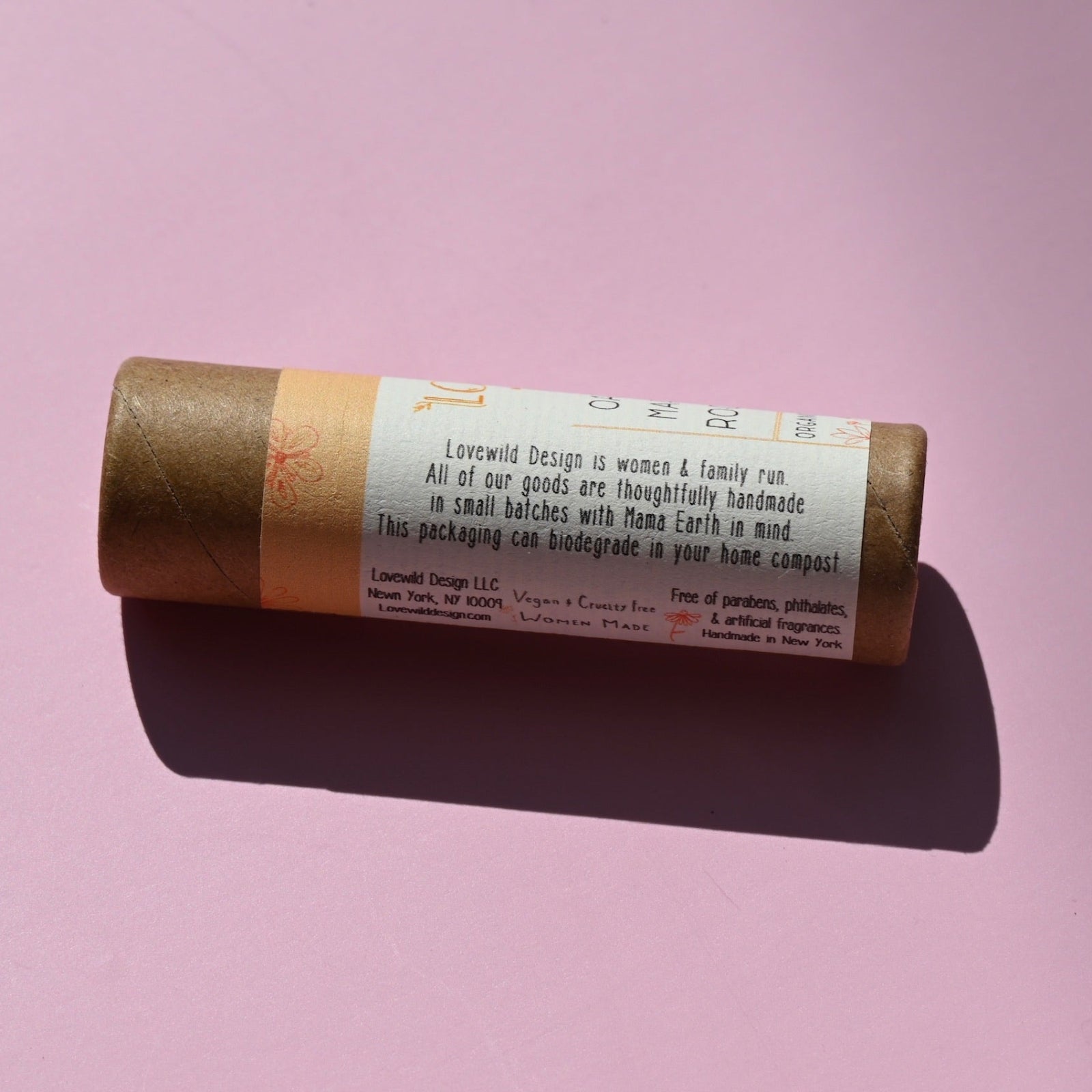The side of the Oat Straw and Marshmallow Root Lip Balm on a pink background.