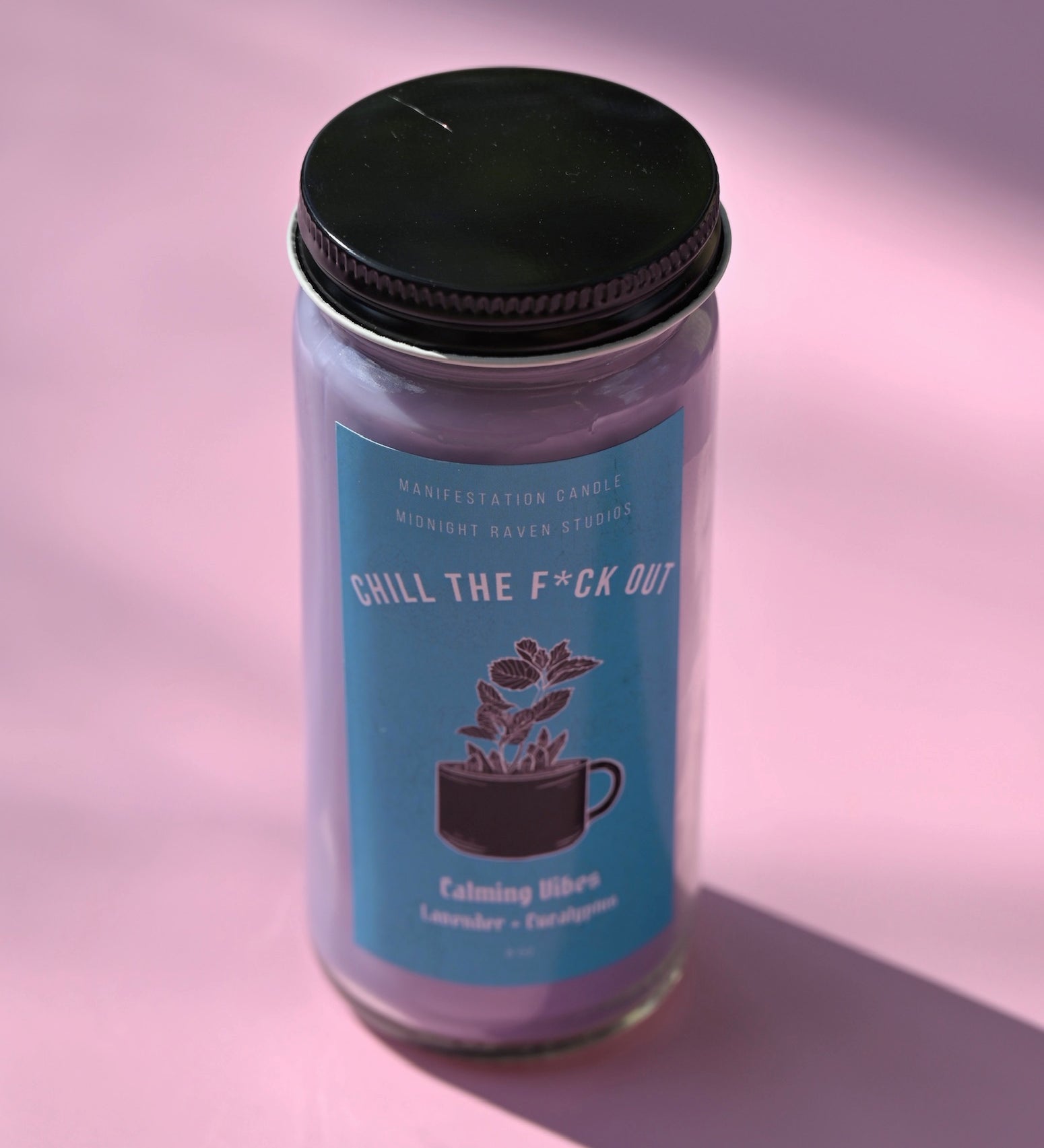 The Chill the F*ck Out Spell Candle with Herbs and Crystals on a pink background.