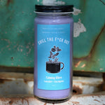 The Chill the F*ck Out Spell Candle with Herbs and Crystals in front of a teal background and on a white rusty surface.