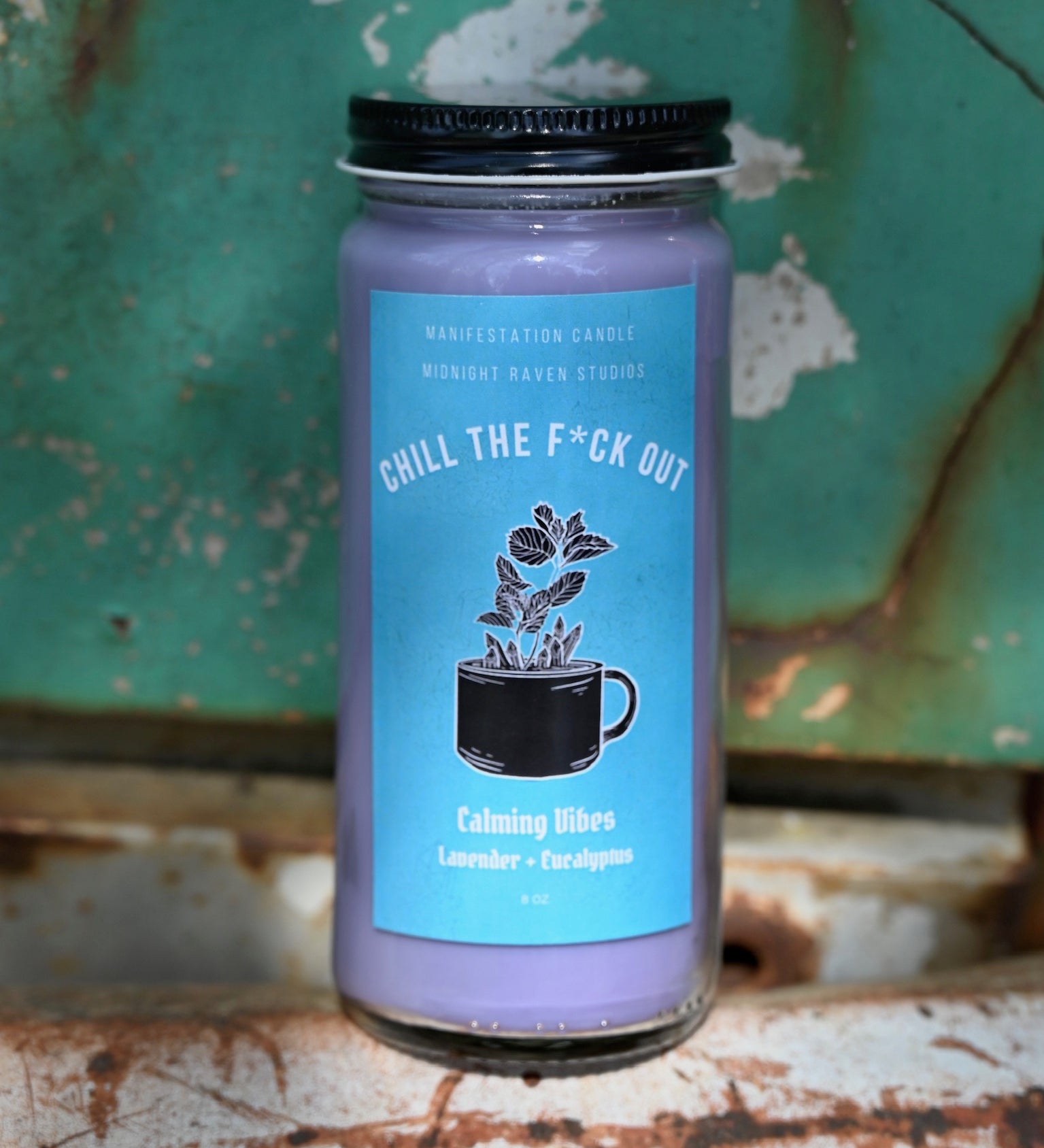 The Chill the F*ck Out Spell Candle with Herbs and Crystals in front of a teal background and on a white rusty surface.