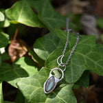 The Labradorite Sterling Silver Celestial Necklace on a green leaf.
