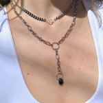 Someone wearing the Garnet Priestess Y Necklace and the Clear Quartz Vibez Choker.