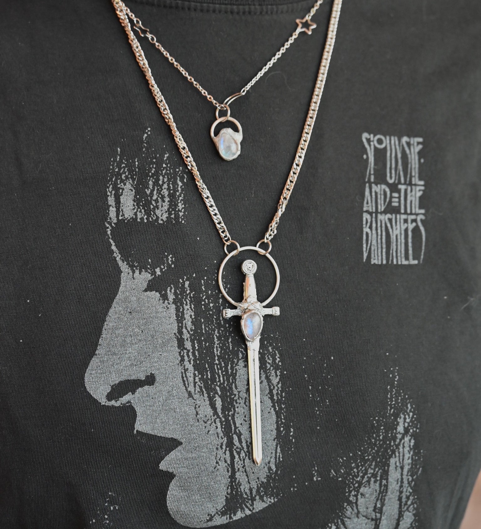 The Stainless Steel Moonstone Sword Necklace and Moonstone Sterling Silver Celestial Necklace being worn by someone.