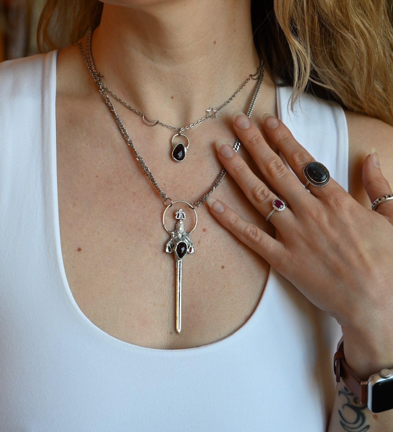 Someone wearing the Sterling Silver Garnet Sword Necklace and the Garnet Sterling Silver Celestial Necklace.