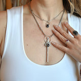 Someone wearing the Sterling Silver Garnet Sword Necklace and the Garnet Sterling Silver Celestial Necklace.