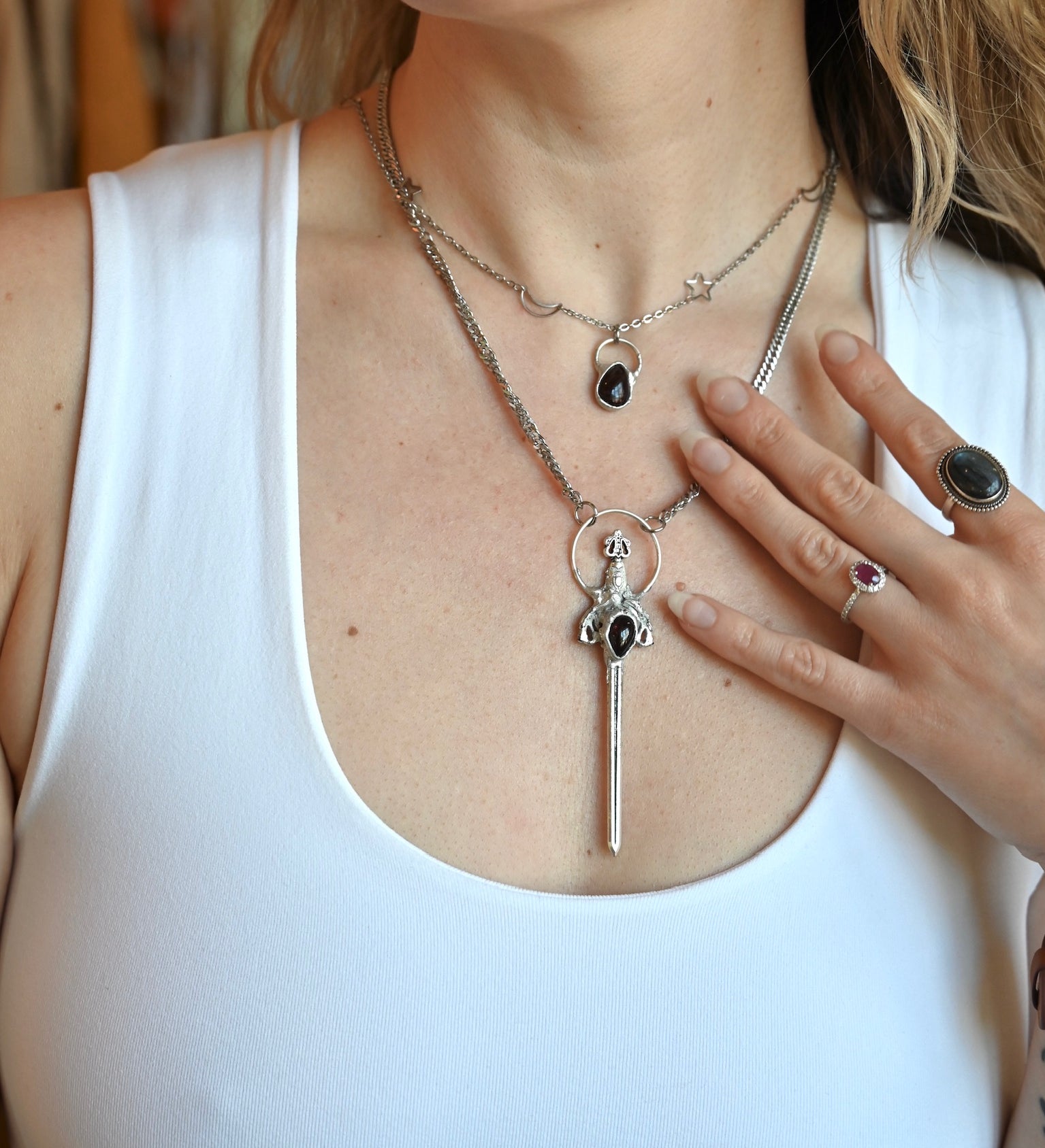 Someone wearing the Sterling Silver Garnet Sword Necklace and the Garnet Sterling Silver Celestial Necklace.