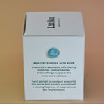 The side of the box of the Amazonite Crystal Bath Bomb on a pink background.