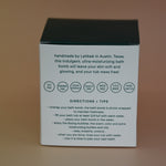 The back of the box of the Hand-Painted Lavender Bath Bomb on a dusty pink background.