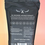 The back of the Black Hatchet Shower Steamers - Grapefruit & Mint Shower Steamers on a pink background.