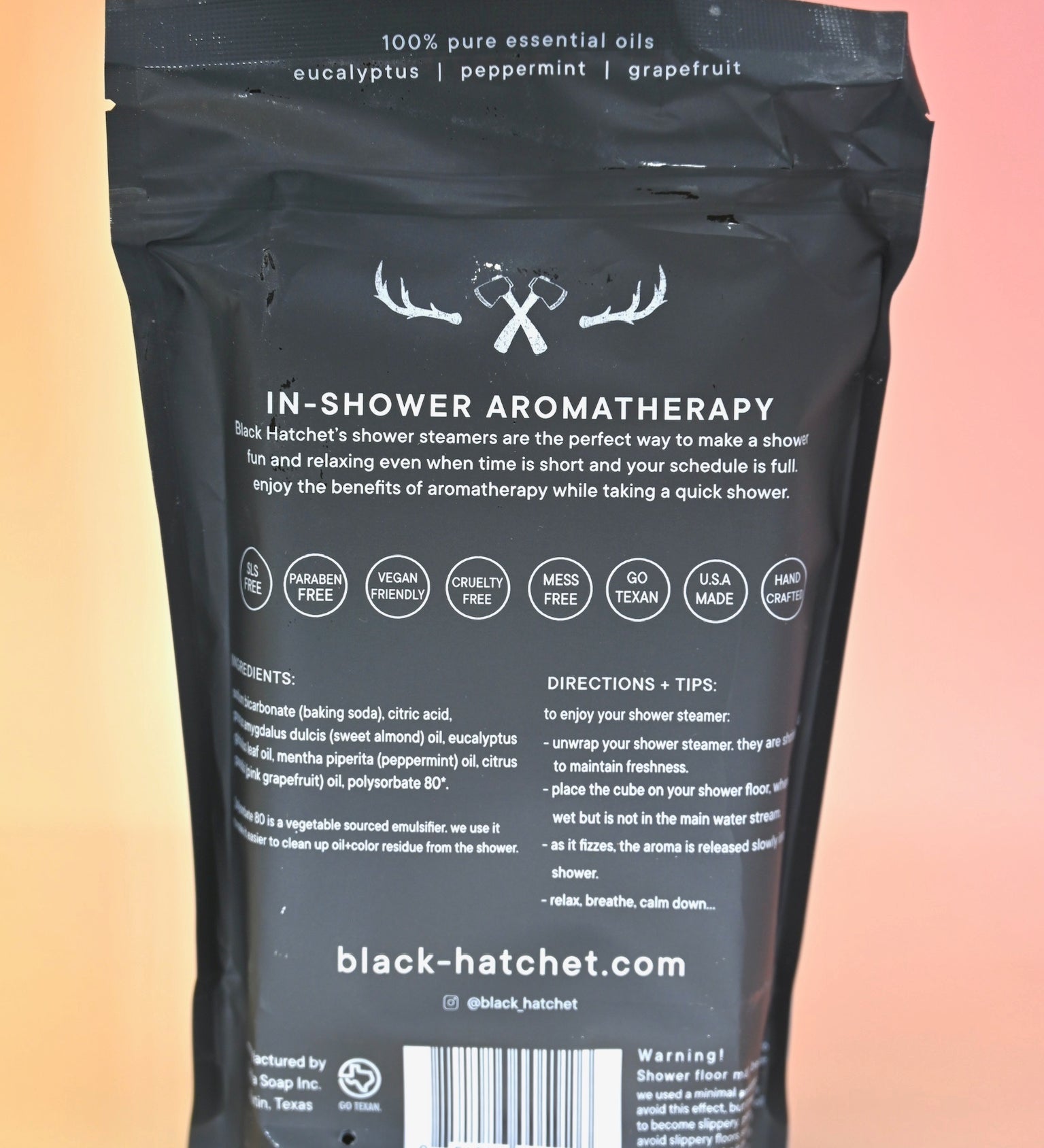 The back of the Black Hatchet Shower Steamers - Grapefruit & Mint Shower Steamers on a pink background.