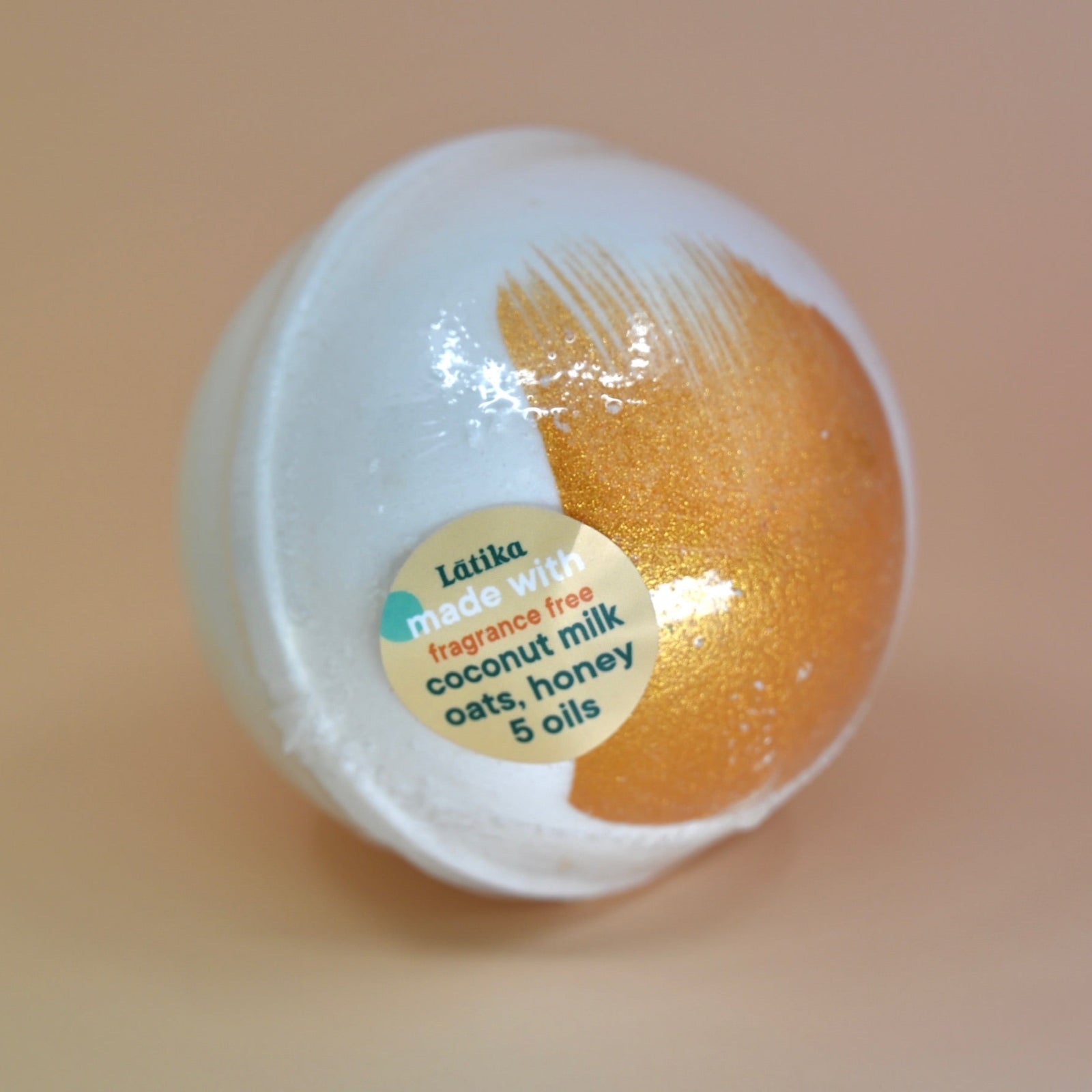 The Fragrance-Free Oat Milk Soothing Bath Bomb on a dusty pink background.