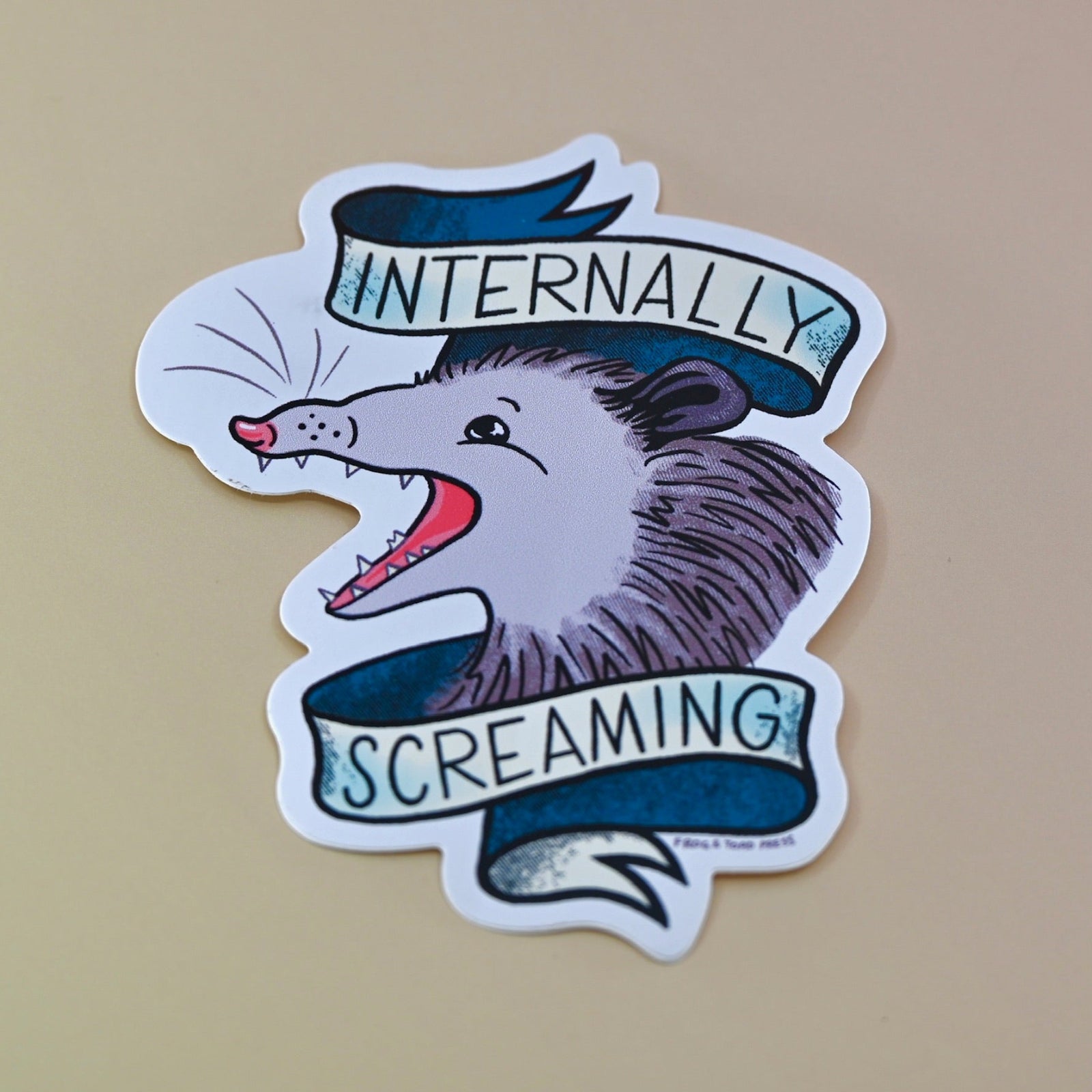 The Internally Screaming Possum Sticker on a tan background.