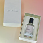 The Dilo Palo Santo 50ml Unisex Eau de Parfum bottle in its box on a light pink background. The box is open showing off the perfume.