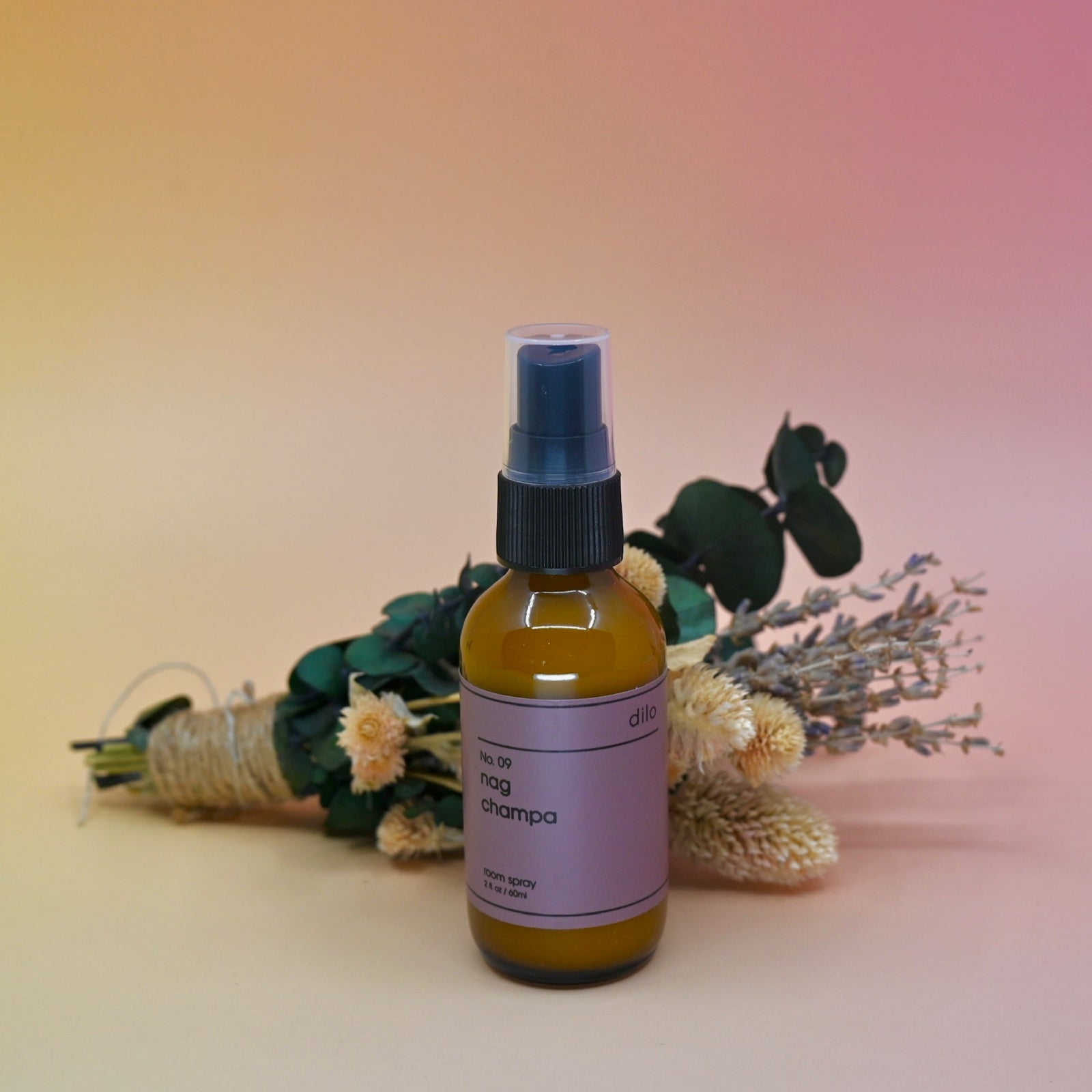 The No. 09 Nag Champa Room Spray in front of a dried flower bundle on a pink background.