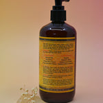 The back of the Essential Oil Cleansing Hand & Body Wash with a crystal in front of it on a light pink background.