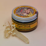 The Essential Oil Sugar Body Scrub with a crystal in front of it on a light pink background.