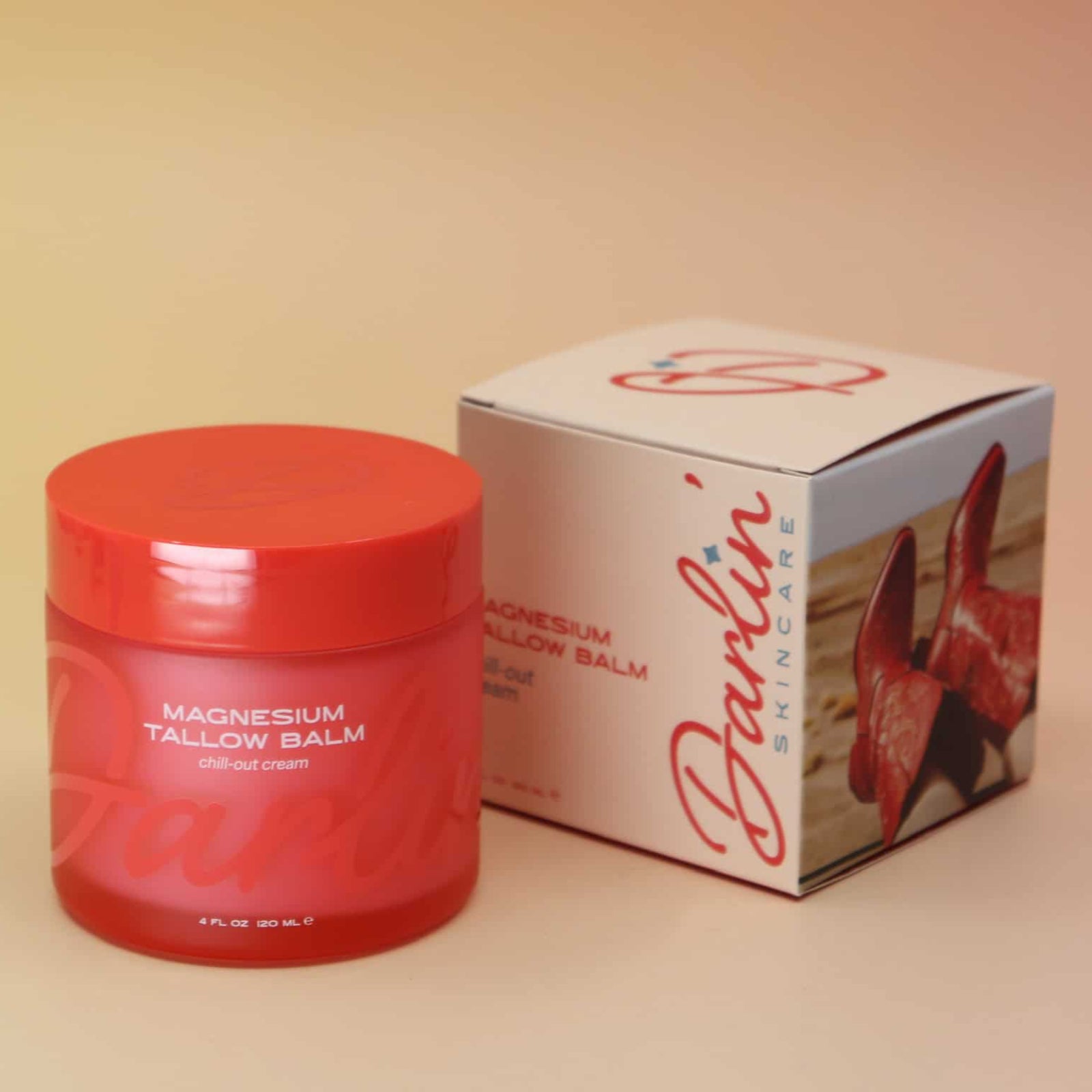 Red jar of magnesium balm with a matching box on a beige background