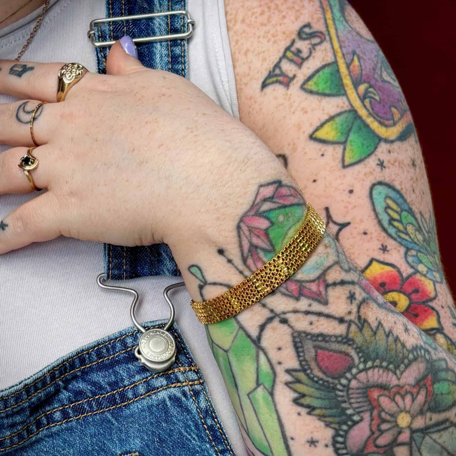 Gold mesh bracelet styled with gold rings and tattoos