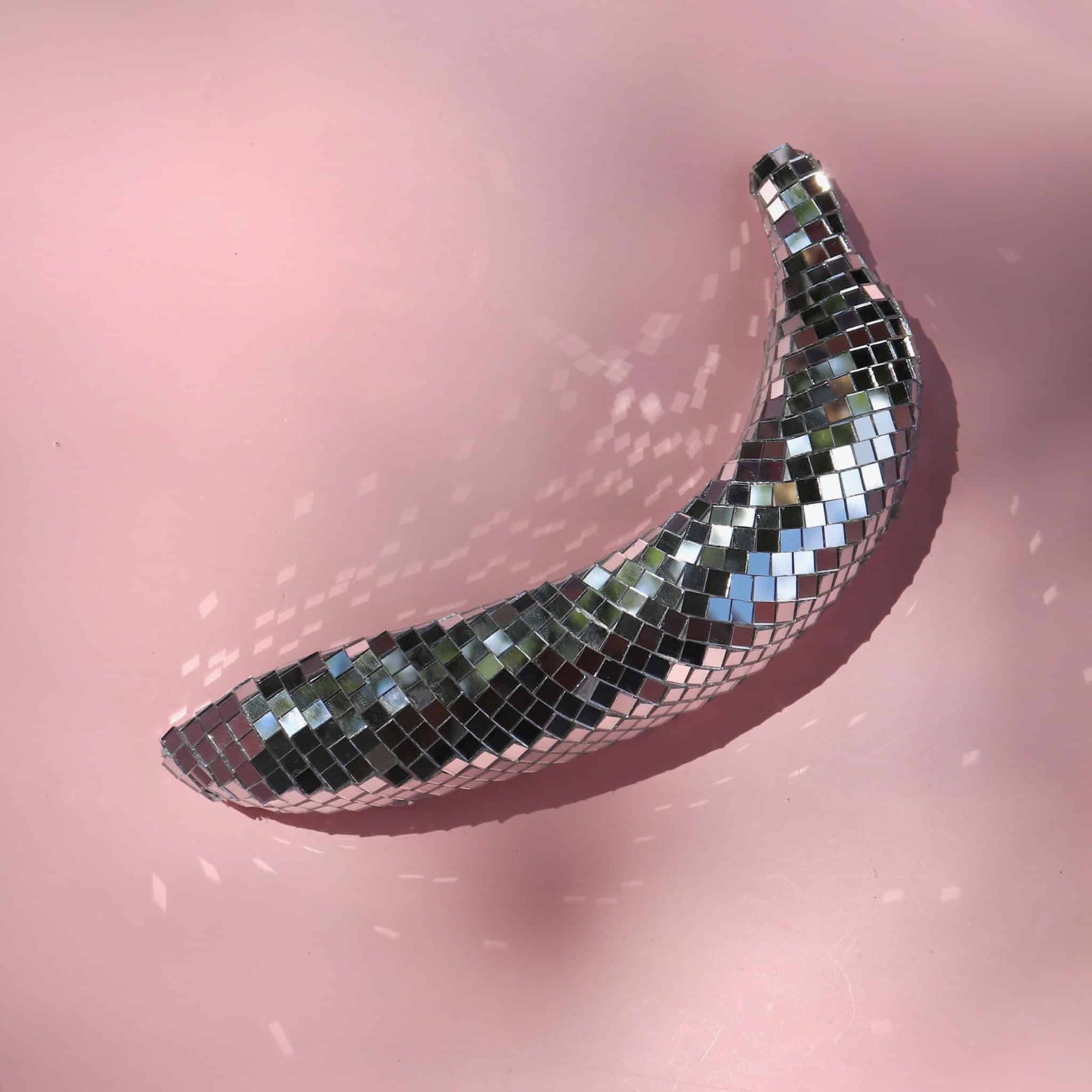 Decorative disco ball shaped like a banana on a pink background