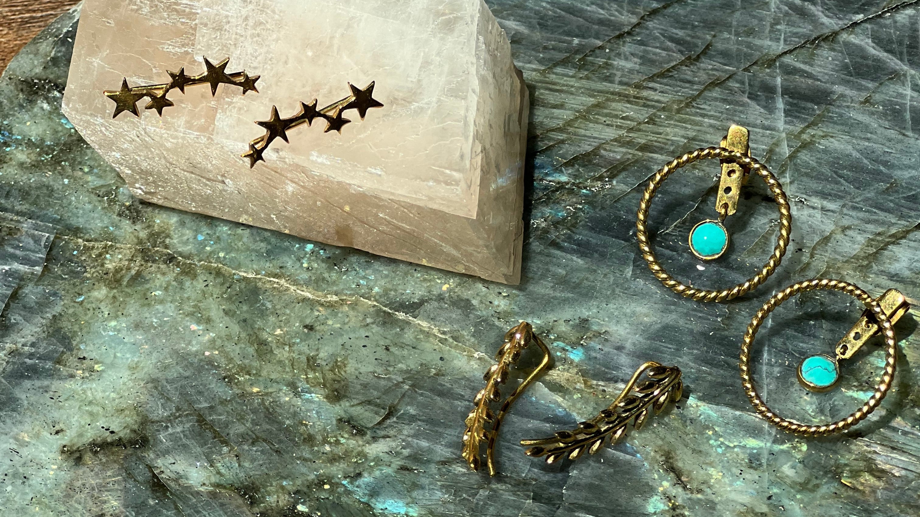 Gold earrings with turquoise stones on a stone surface