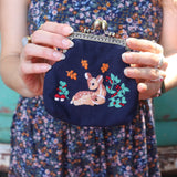 A woman in a navy floral dress holding the Deer Embroidered Navy Blue Coin Purse.