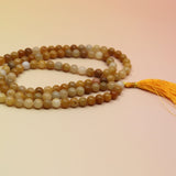 Golden Healer 108 Mala Necklace on pink and orange background
