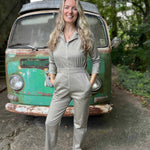 Woman in a gray jumpsuit standing in front of a vintage green van.