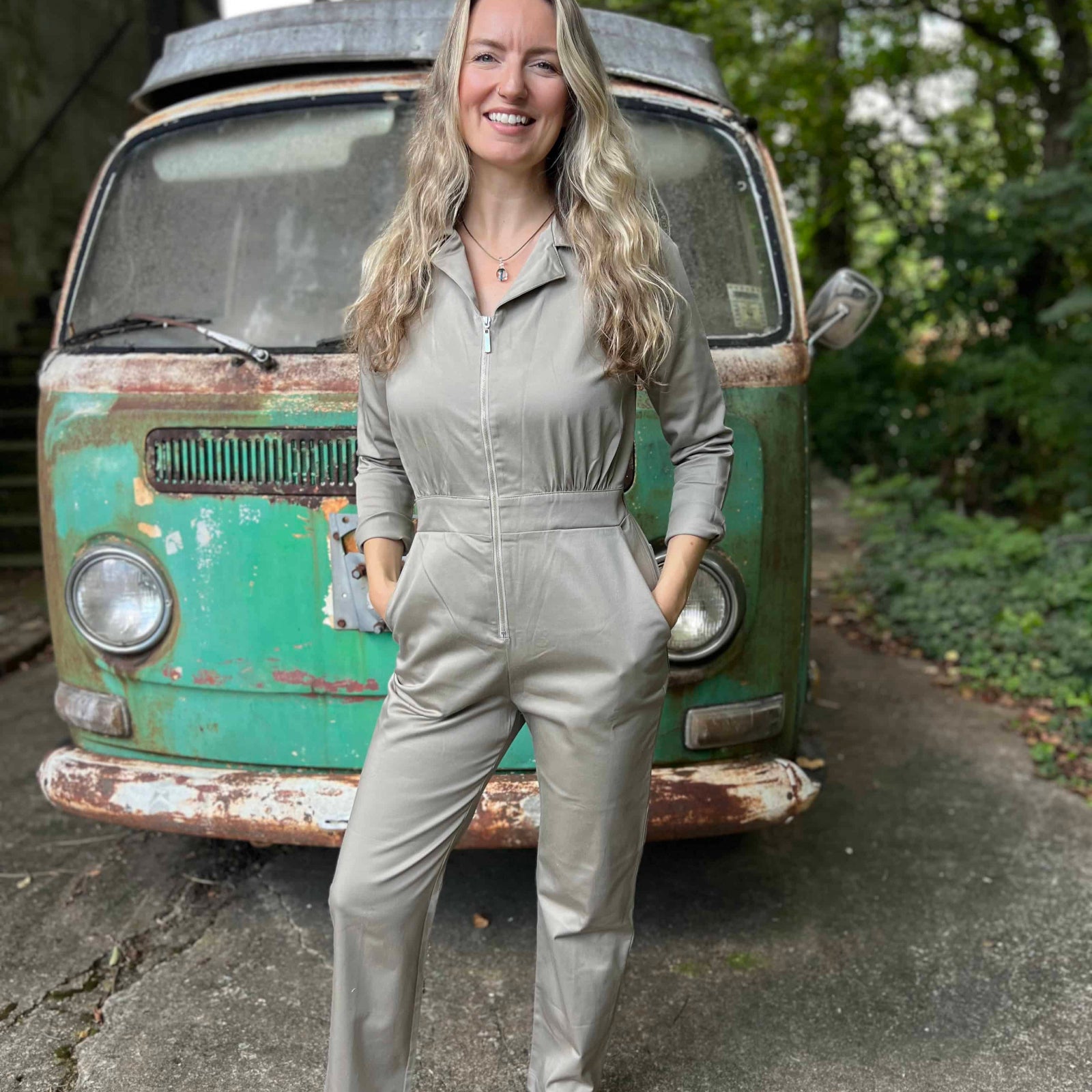 Woman in a gray jumpsuit standing in front of a vintage green van.