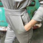 Person wearing a gray outfit with a teal background