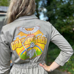 Person wearing a beige jacket with a Grateful Dead logo on the back, standing outdoors.