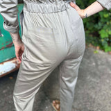 Person wearing light gray pants with a green patch on a blurred background